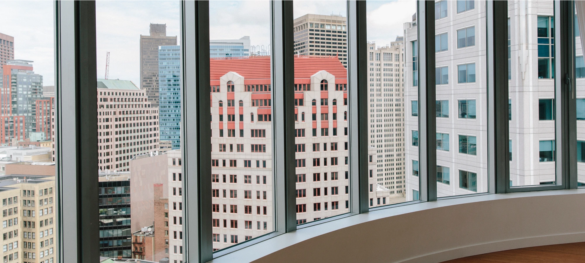 Office interior with curved glass windows offering a scenic view of downtown skyscrapers