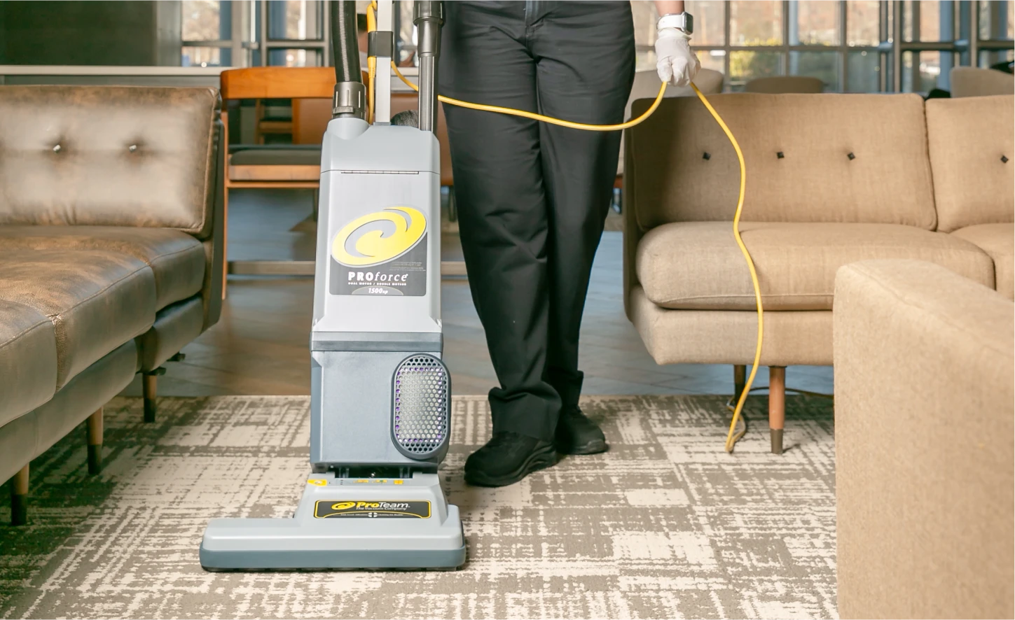 Professional vacuuming a commercial carpeted area using a ProForce upright vacuum cleaner