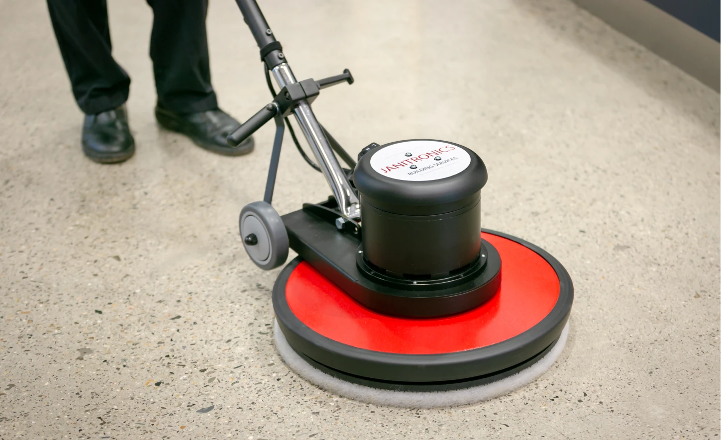 Janitronics-branded floor buffer machine polishing a concrete floor for a spotless finish