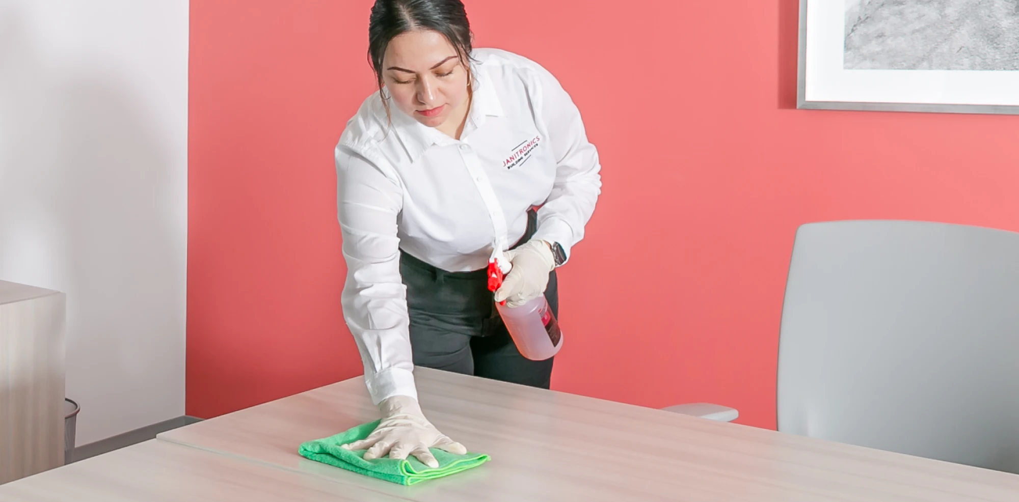 Office cleaner in gloves disinfecting a workspace against germs and bacteria
