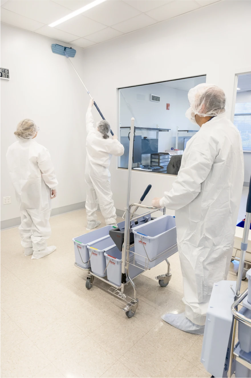 Cleanroom janitorial team cleaning walls and surfaces with specialized equipment
