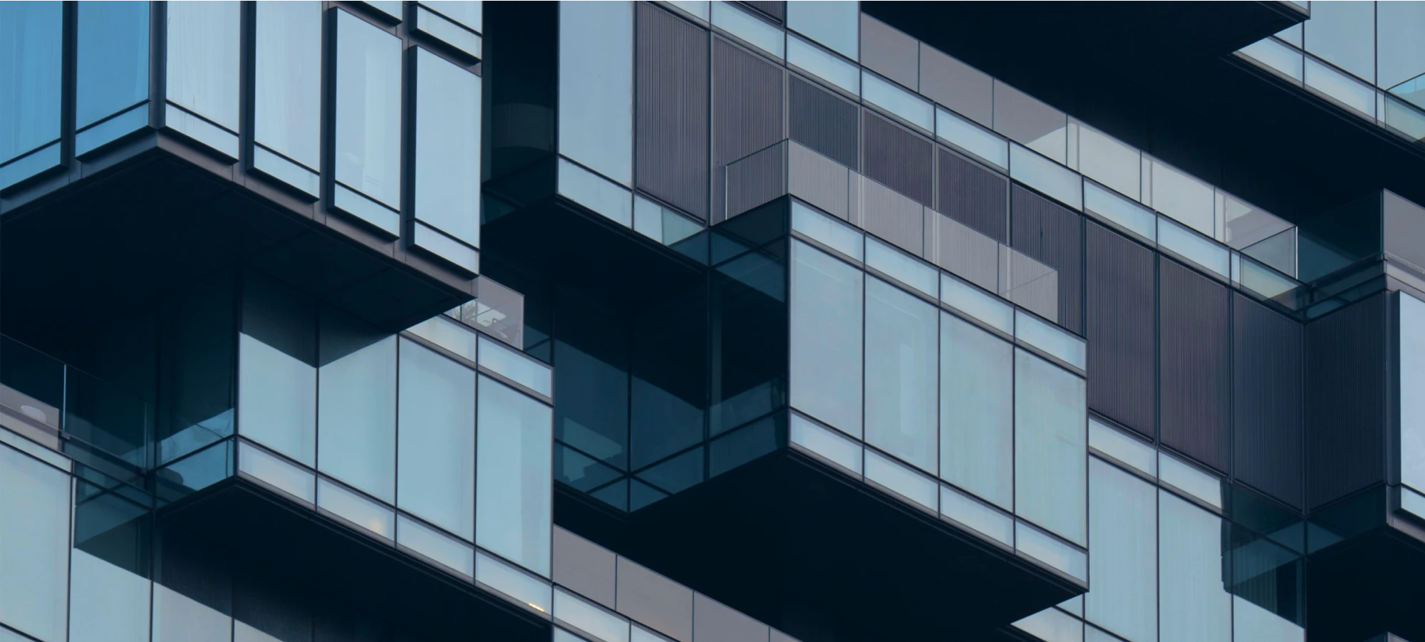 Geometric glass building showcasing staggered balconies and dark metal panels