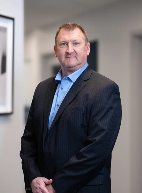 Professional man in pinstripe suit posing confidently in corporate hallway with neutral backdrop