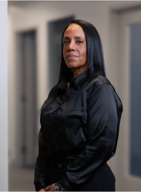 Businesswoman wearing black satin blouse posing confidently in professional office hallway