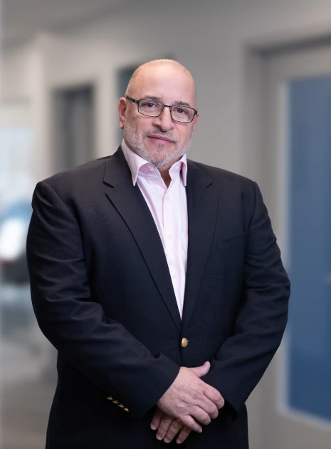 Professional headshot of experienced executive wearing glasses and stylish buttoned suit