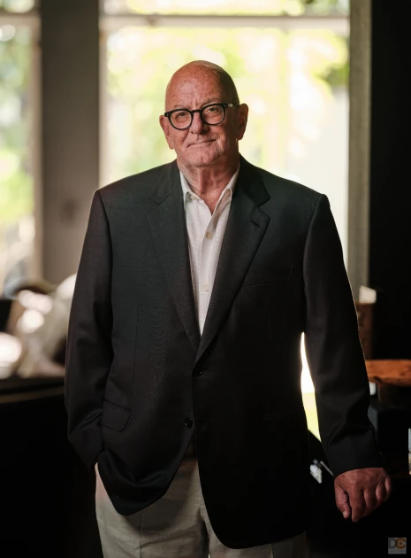 Senior executive wearing glasses and standing confidently in warmly lit office environment