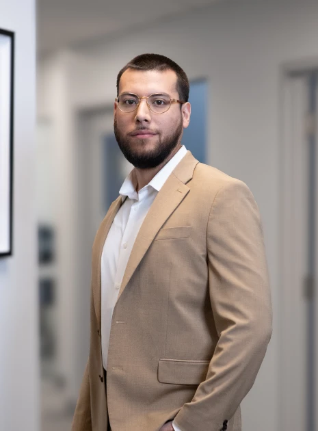 Corporate portrait of bearded man wearing tan blazer and white shirt in professional setting