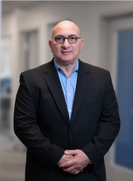 Business leader standing with hands clasped, dressed formally in office setting