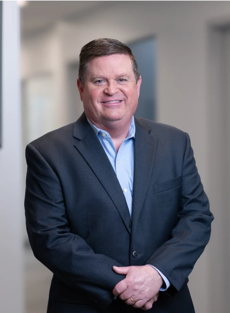 Professional man in dark blazer and light shirt smiling confidently in office hallway