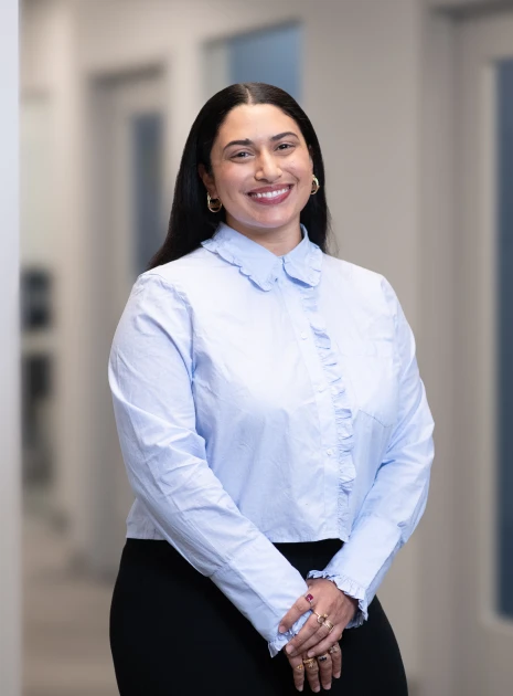 Professional female employee in light blue shirt standing with poise and friendly expression