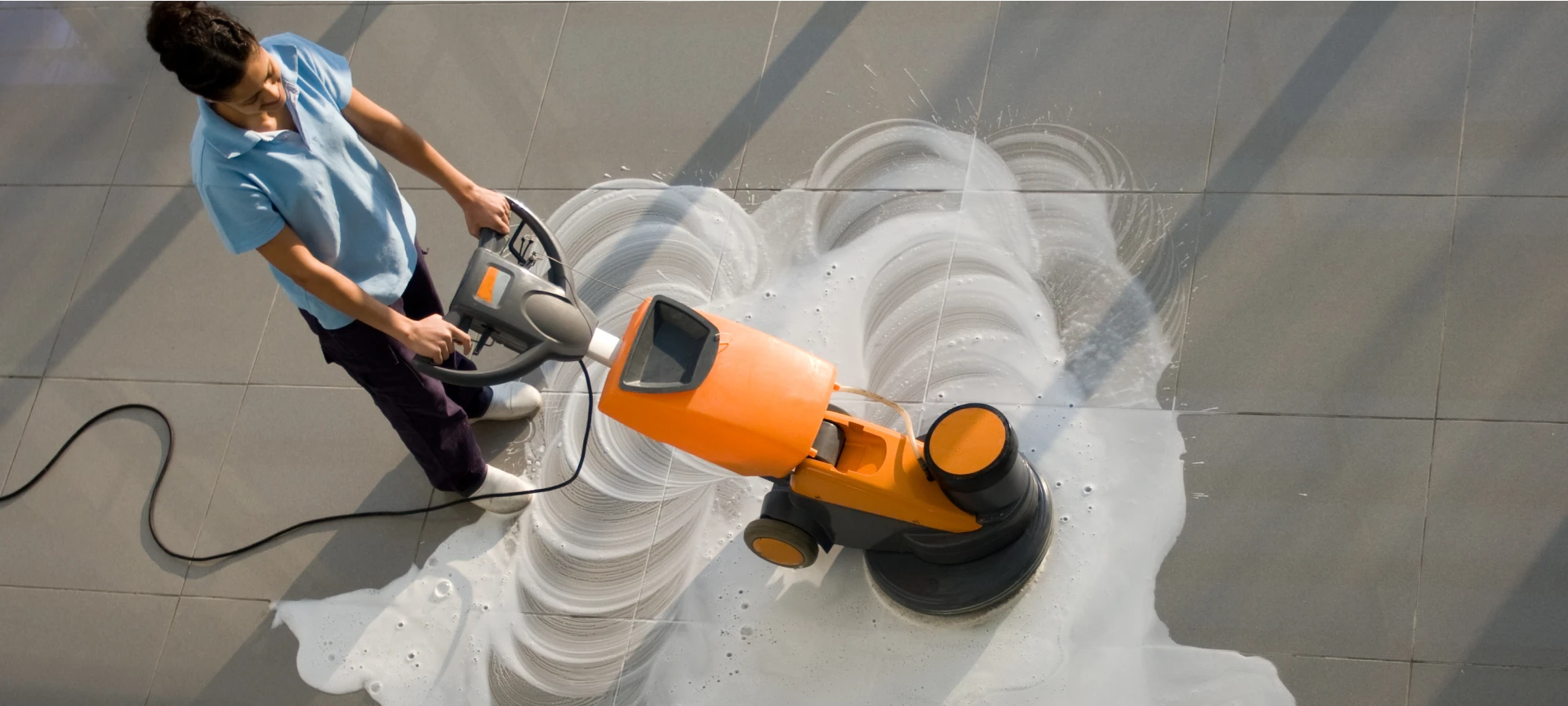 Professional floor cleaning with a high-powered machine creating swirling soap patterns