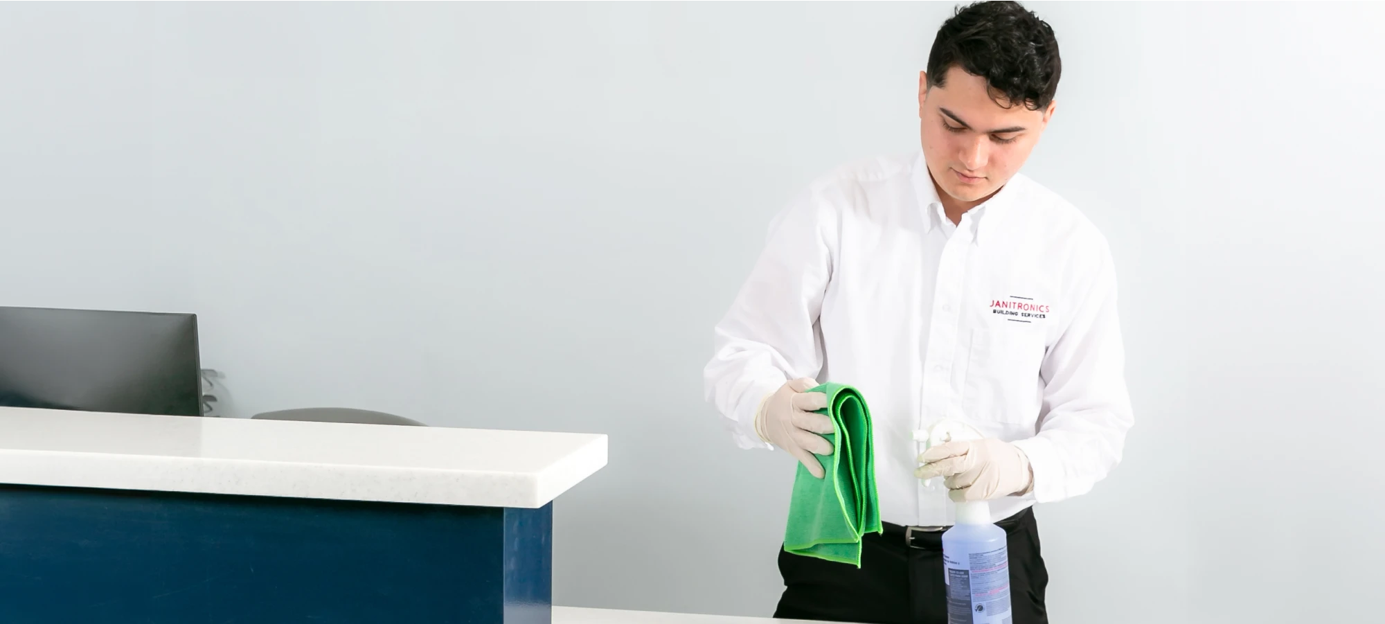 Janitorial worker preparing disinfectant and cloth for cleaning a reception desk