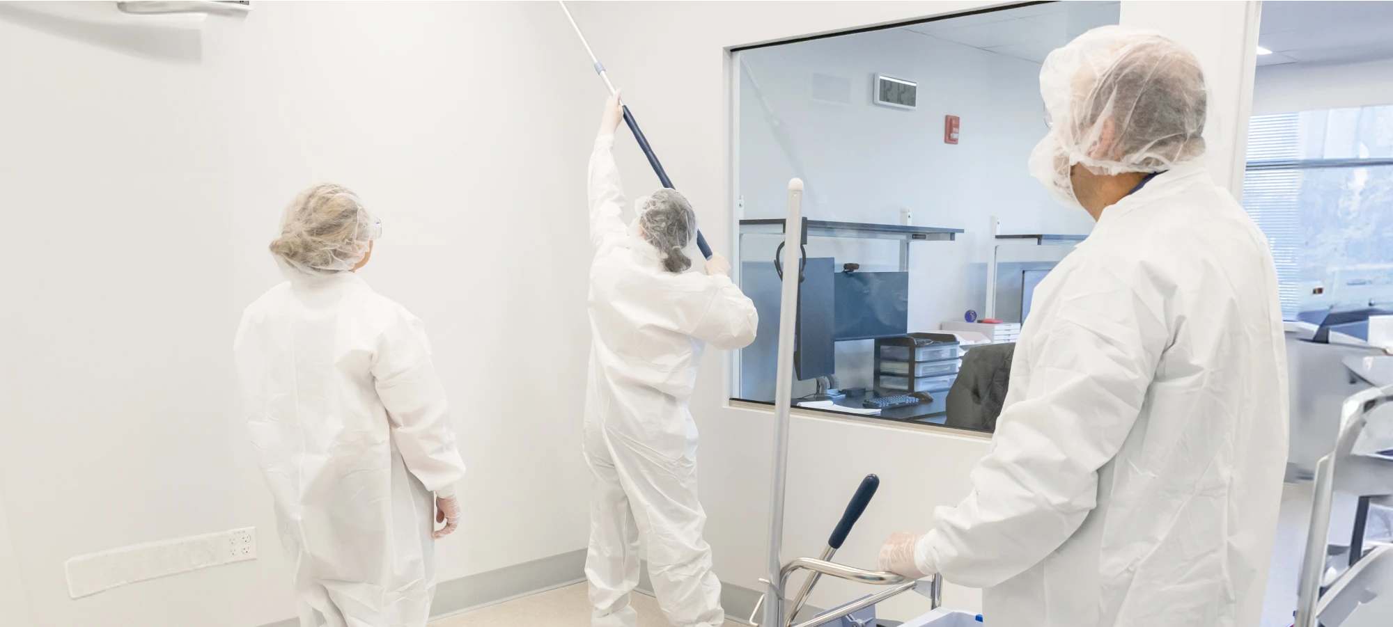 Workers in protective suits performing contamination-free handling in a cleanroom
