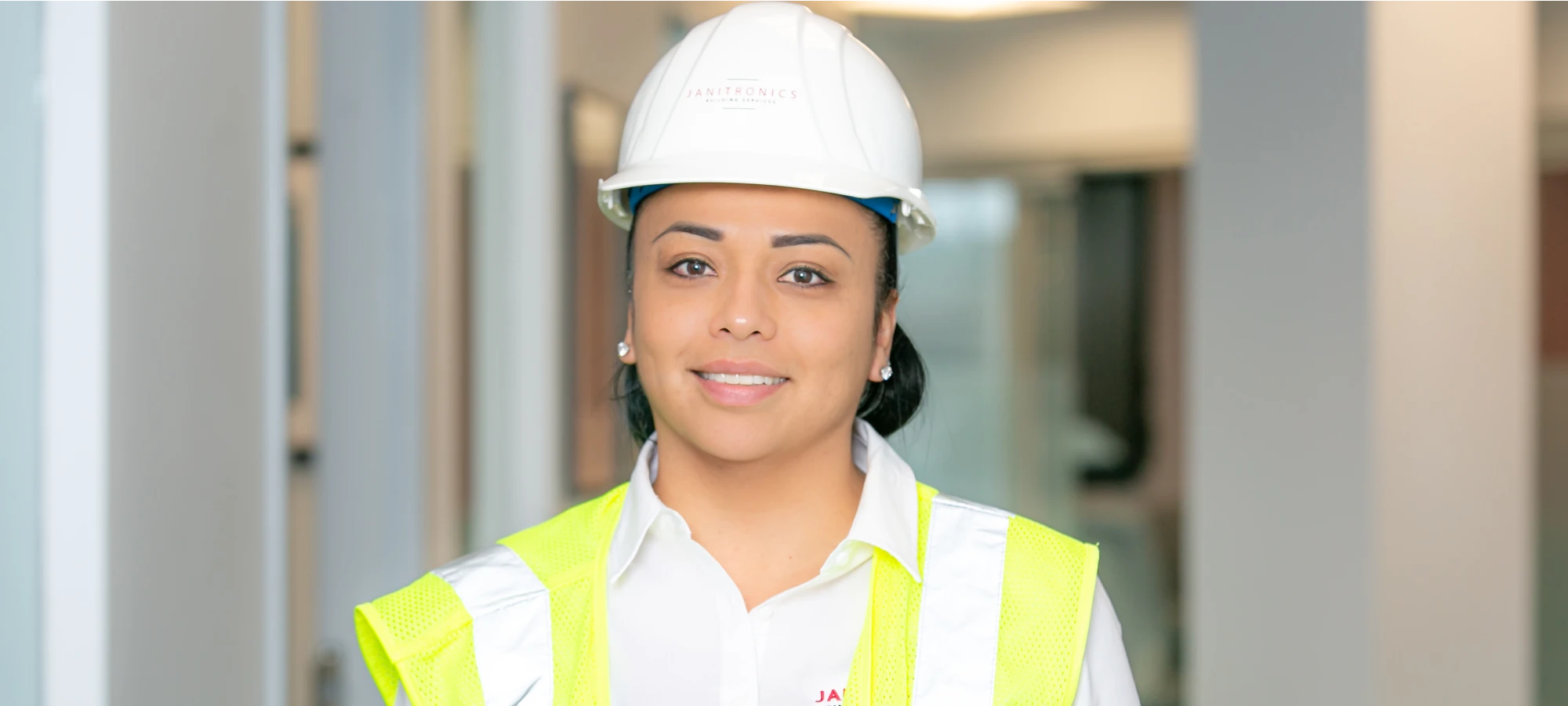 Janitronics employee in a hard hat and safety vest posing in a professional setting
