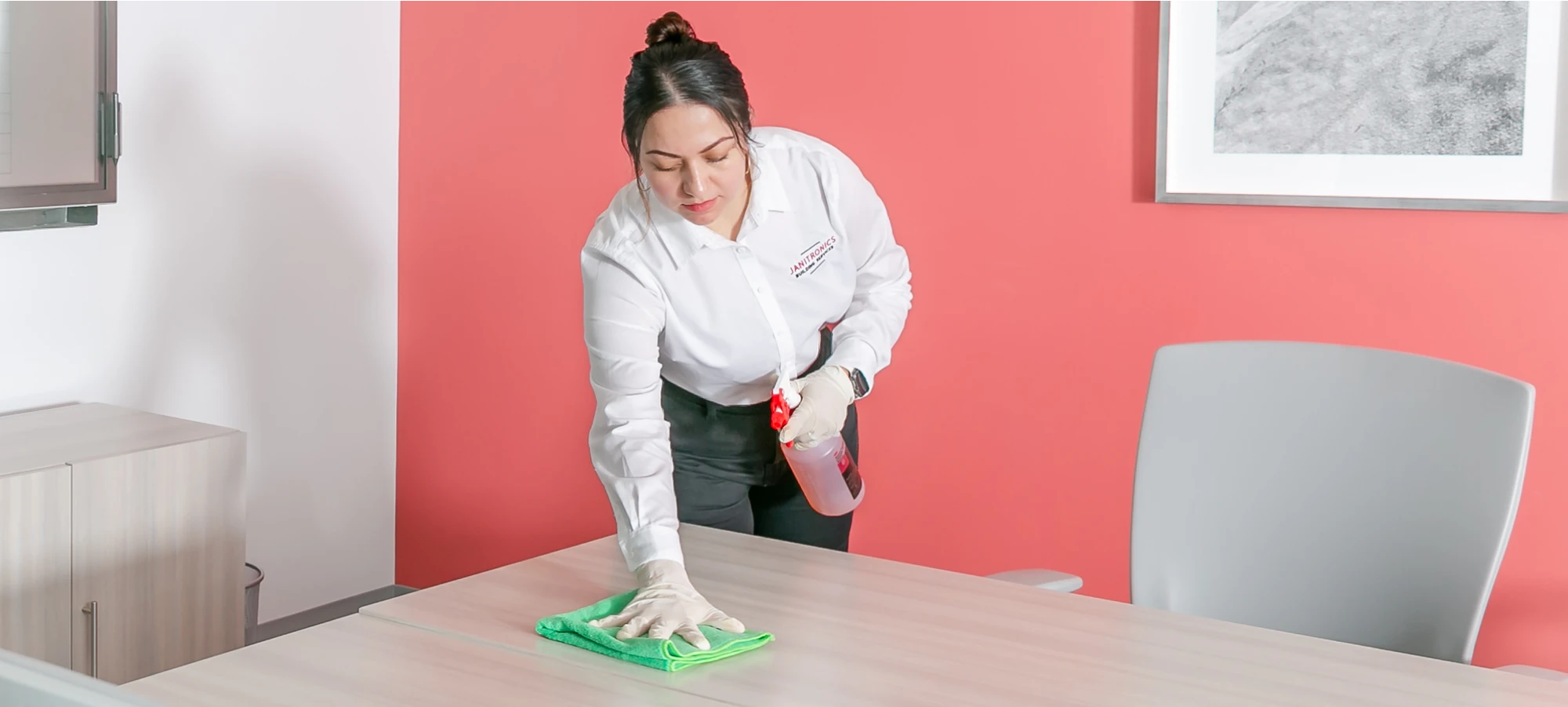 Professional cleaner wiping down a conference table with disinfectant spray