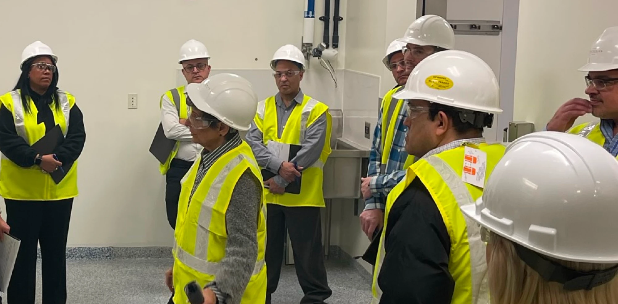 Safety training session with workers wearing hard hats and high-visibility vests indoors